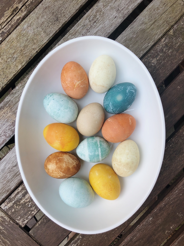 Naturally colored Easter eggs from vegetable dyes sitting in an oval bowl on a table